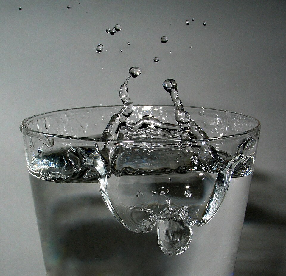 A drop splashing into a glass of water